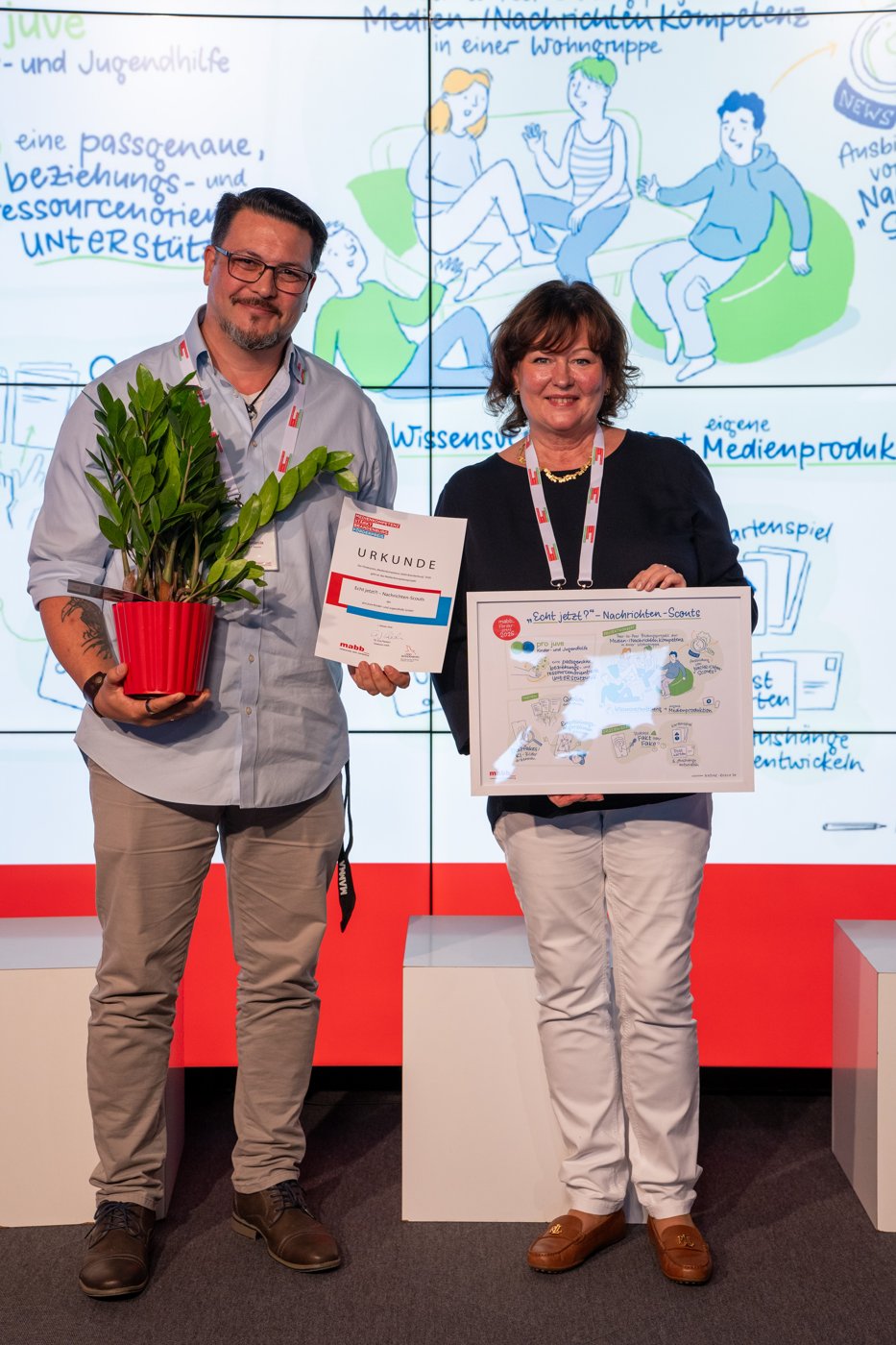 Preisverleihung auf der Netzwerktagung 2026 mit Urkunde und gerahmtem Graphic Recording zum Projekt Echt jetzt?! Nachrichten-Scouts von pro juve